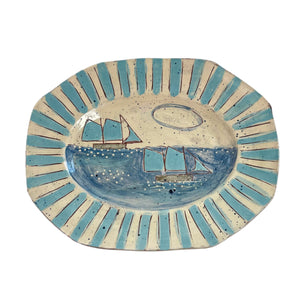 Ceramic plate with blue and beige design of sailboats on a white background